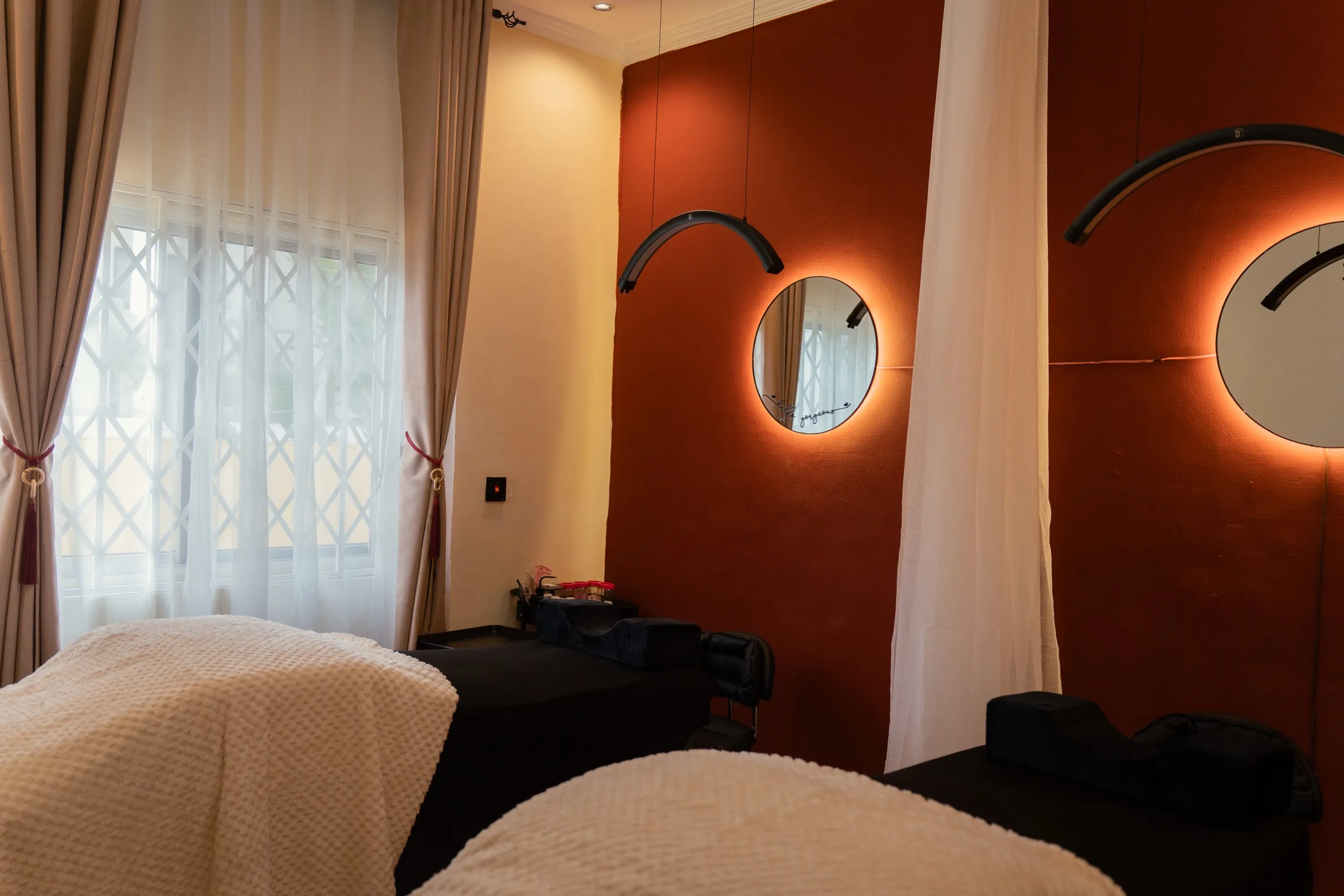 The lash and brow treatment room at Mink'd by Mya, with backlit mirrors on a deep burgundy wall